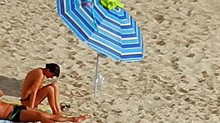 A topless European girl spies on others at the beach in Greece